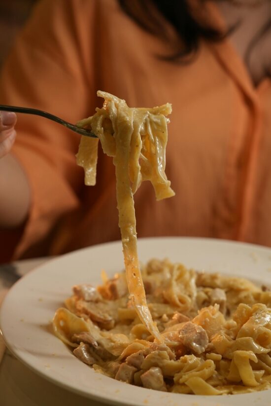 A creamy fettuccine alfredo pasta being enjoyed at a cozy restaurant setting.