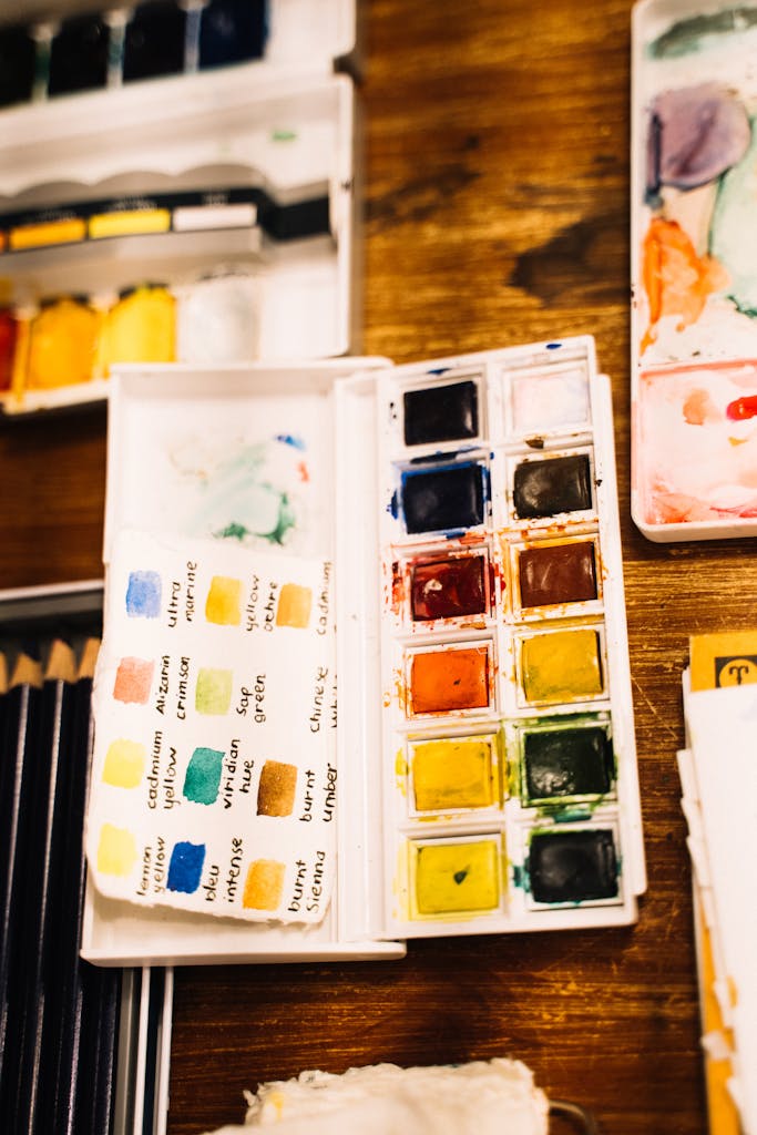 A watercolor palette with vibrant colors and swatches arranged neatly on a wooden surface.