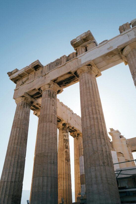 Low angle view of the ancient Parthenon columns against a clear blue sky in Athens, Greece.